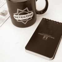 Detective's mug and notebook with a fingerprint card in the background