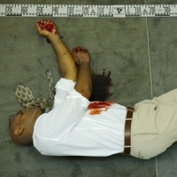 Man lying on his side on the floor with blood on the front of his shirt and the floor in front of him