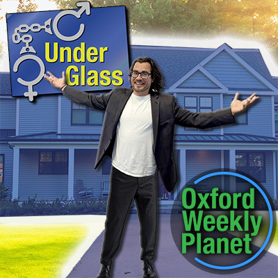 Dark-haired smiling man with arms extended standing in front of a residence with the Under Glass logo next to him with the Oxford Weekly Planet logo in the foreground