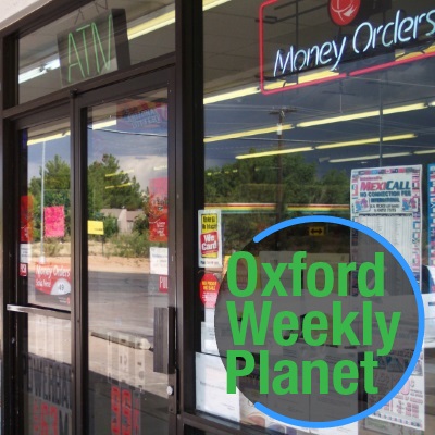 Convenience store entrance with Oxford Weekly Planet logo in the foreground of the bottom right corner