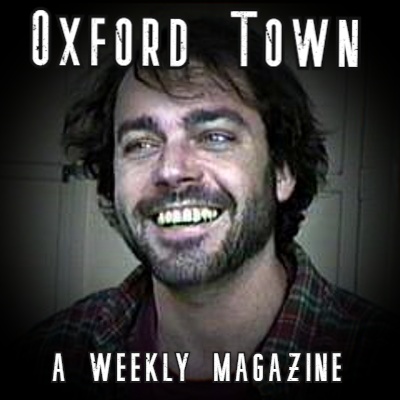 Smiling man with dark hair, beard and mustache with "Oxford Town A Weekly Magazine" in the foreground
