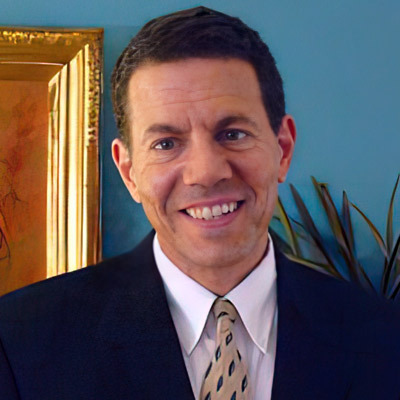 Smiling man with short dark hair and wearing a suit and tie