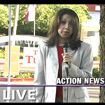 Female reporter with long dark hair in front of an apartment complex