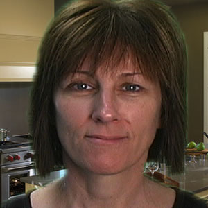 Slightly smiling woman with short dark hair and bangs