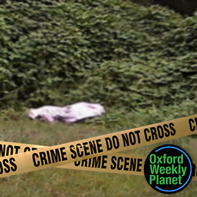 Crime scene tape in front of a covered body in a grassy location with the Oxford Weekly Planet logo in the foreground