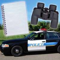Spiral notebook, binoculars, and a marked police car