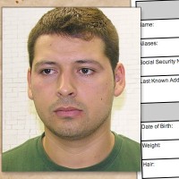 Man with short brown hair with a criminal history form in the background