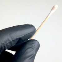 Gloved hand holding a swab with a reddish stain on the end