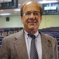 Smiling balding man with glasses in a lecture hall