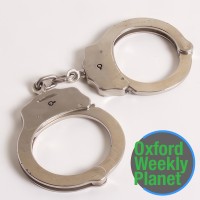 Handcuffs with the Oxford Weekly Planet logo in the foreground