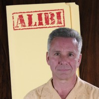 Man with short salt-and-pepper hair in front of a manila folder stamped 'Alibi'