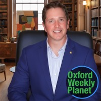 Serious man with short brown hair in a library with the Oxford Weekly Planet logo in the foreground