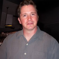 Serious man with short brown hair with an unidentified person beside him