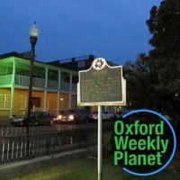 Historical marker on the Oxford, MS city square with the Oxford Weekly Planet logo in the foreground