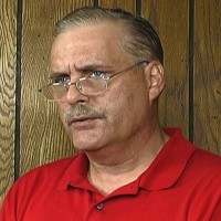 Older man with glasses, thinning gray hair and a mustache