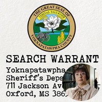 Seal of Yoknapatawpha County with the label 'Search Warrant' with an inset of a smiling woman with a short dark bob haircut and glasses