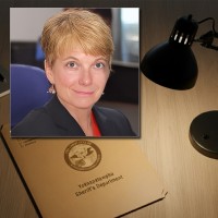 Woman with a salt-and-pepper pixie cut in front of a manila folder stamped "Alibi"