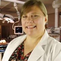 Smiling woman wearing a lab coat in a medical setting