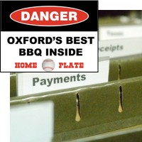 Hanging files with finance-related labels with an inset of a warning sign reading "Danger. Oxford's best BBQ inside. Home Plate" in the foreground