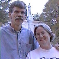 A man with salt and pepper hair and mustache and a smiling woman with silver hair