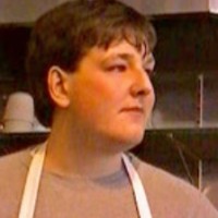 Young man with brown hair wearing a work apron