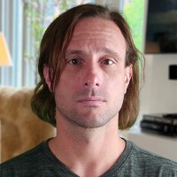 Serious-looking man with chin-length brown hair