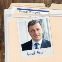 Photo of a man with dark hair, graying at the temples, clipped to a manila folder