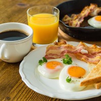 Breakfast of coffee, orange juice, bacon, eggs and toast