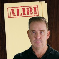 Man with reddish-brown hair in front of a manila folder stamped 'Alibi'