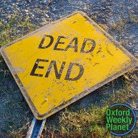 Dead End street sign lying on the ground with the Oxford Weekly Planet logo in the foreground
