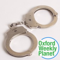 Handcuffs with the Oxford Weekly Planet logo in the foreground