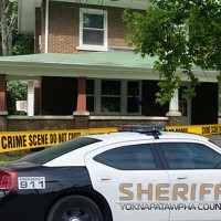 Sheriff's patrol car in front of a house blocked off by crime scene tape