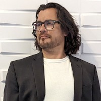 Man with medium-length dark hair and glasses