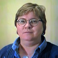 Unsmiling woman with short hair and glasses