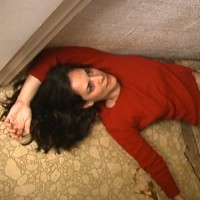 Brunette woman in a long-sleeved red shirt, lying on the floor
