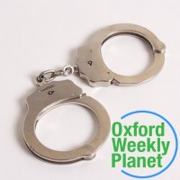 Handcuffs with the Oxford Weekly Planet logo in the foreground