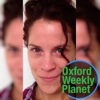 Smiling woman with dark hair with the Oxford Weekly Planet logo in the foreground