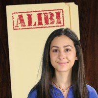 Smiling teen girl with long dark hair in front of a manila folder stamped 'Alibi'