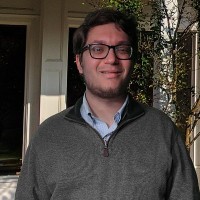 Young man with glasses, dark hair, and a scruffy beard