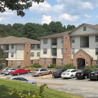 Three-story apartment buildings with vehicles parked outside