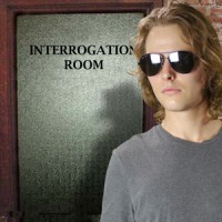 Man with shaggy blond hair and sunglasses in front of the interrogation room door