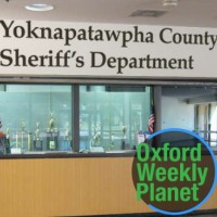 Front desk of the Yoknapatawpha County Sheriff's Department with the Oxford Weekly Planet logo in the foreground