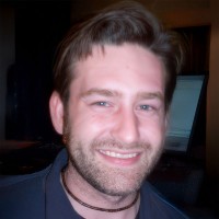 Smiling man with short hair and scruffy facial hair