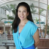 Woman with long dark hair standing in the atrium of a shopping mall