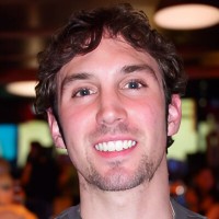 Smiling man with wavy dark hair and scruffy facial hair