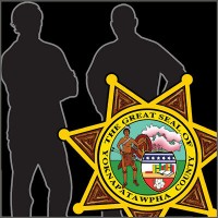 Two men in silhouette with the sheriff's department star in the foreground