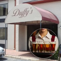 Silhouette of a waitress holding a tray in front of a photo of Duffy's bar