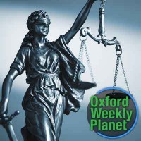 Figure of Lady Justice with the Oxford Weekly Planet logo in the foreground