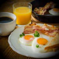 Breakfast of coffee, orange juice, bacon, eggs and toast