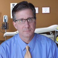 Dark-haired man with glasses in a doctor's exam room